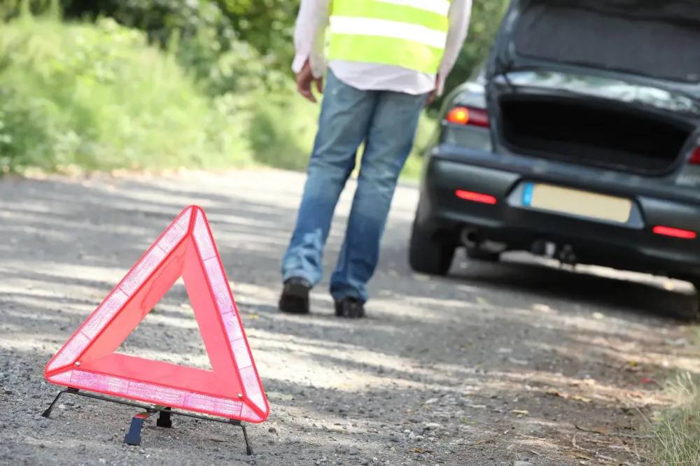 Man setting out hazard triangle from car emergency kit at breakdown